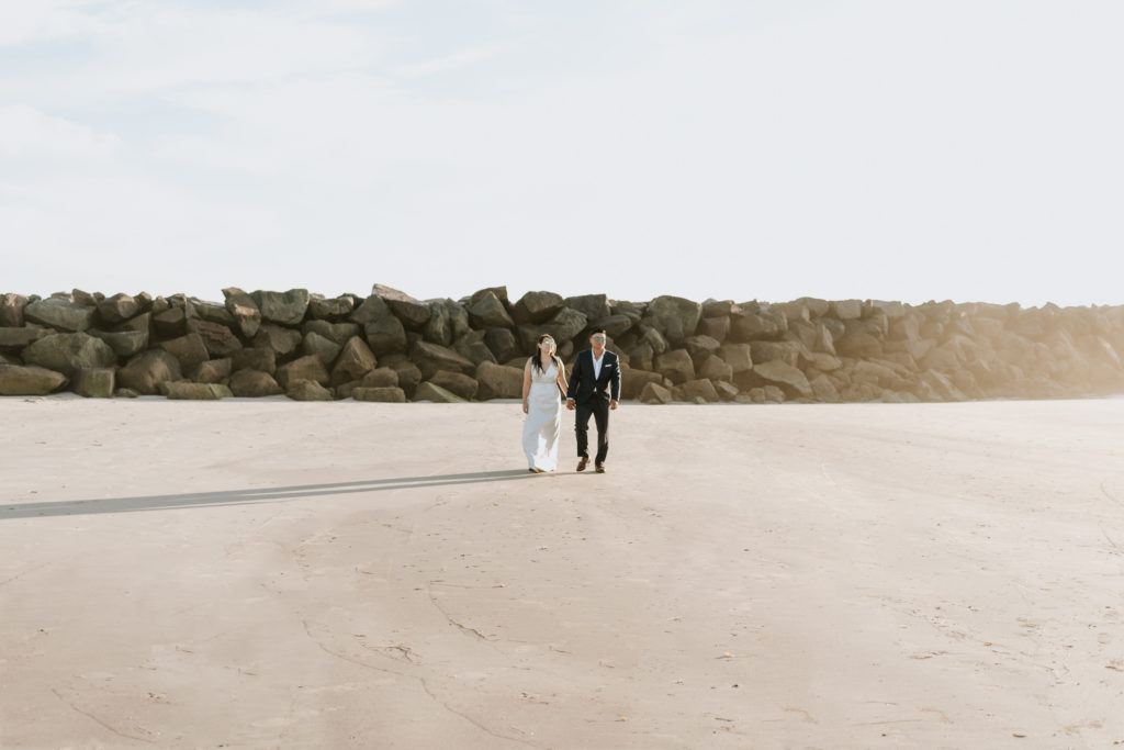 A bride and groom walking during their elopement at Mission Beach in San Diego.