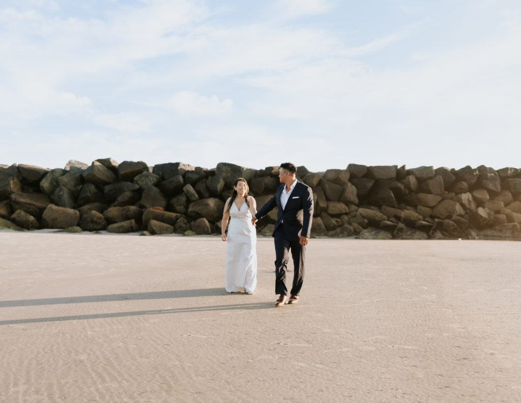 A bride and groom walking at Mission Beach in San Diego during their elopement.