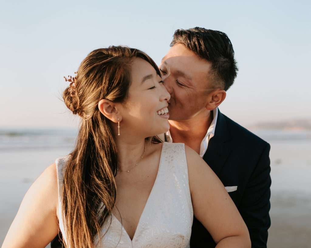 A bride and groom kissing during their elopement at Mission Beach in San Diego.