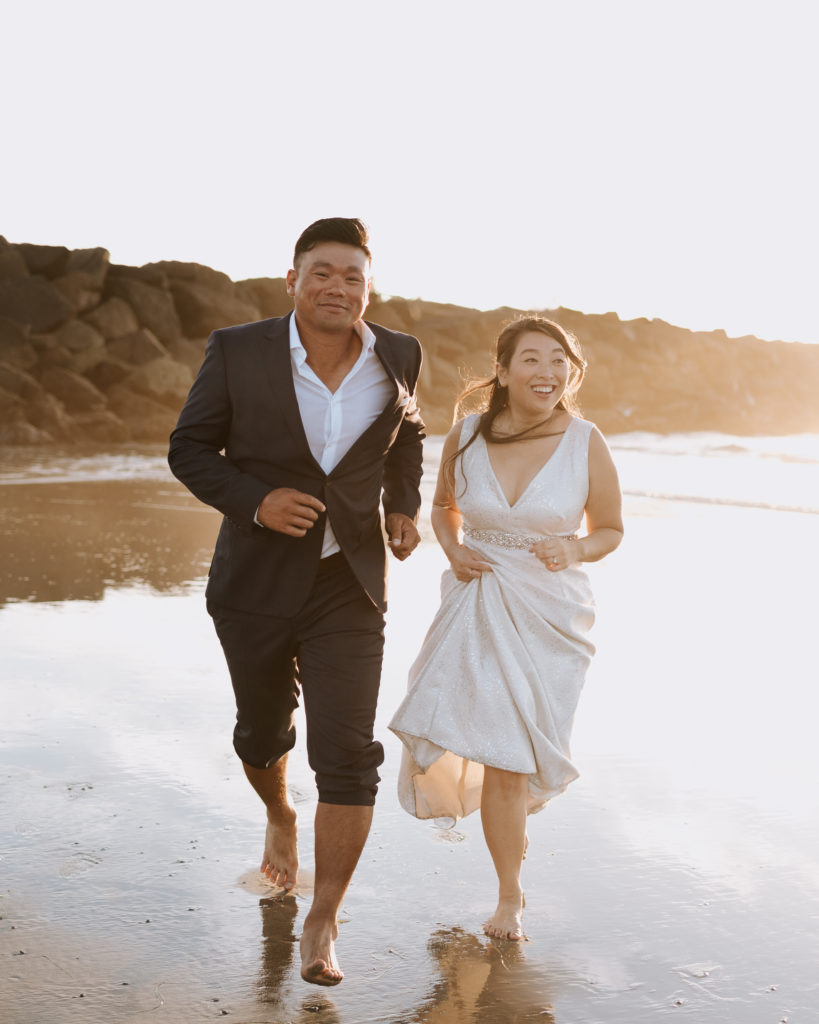 A bride and groom running during their elopement at Mission Beach in San Diego.