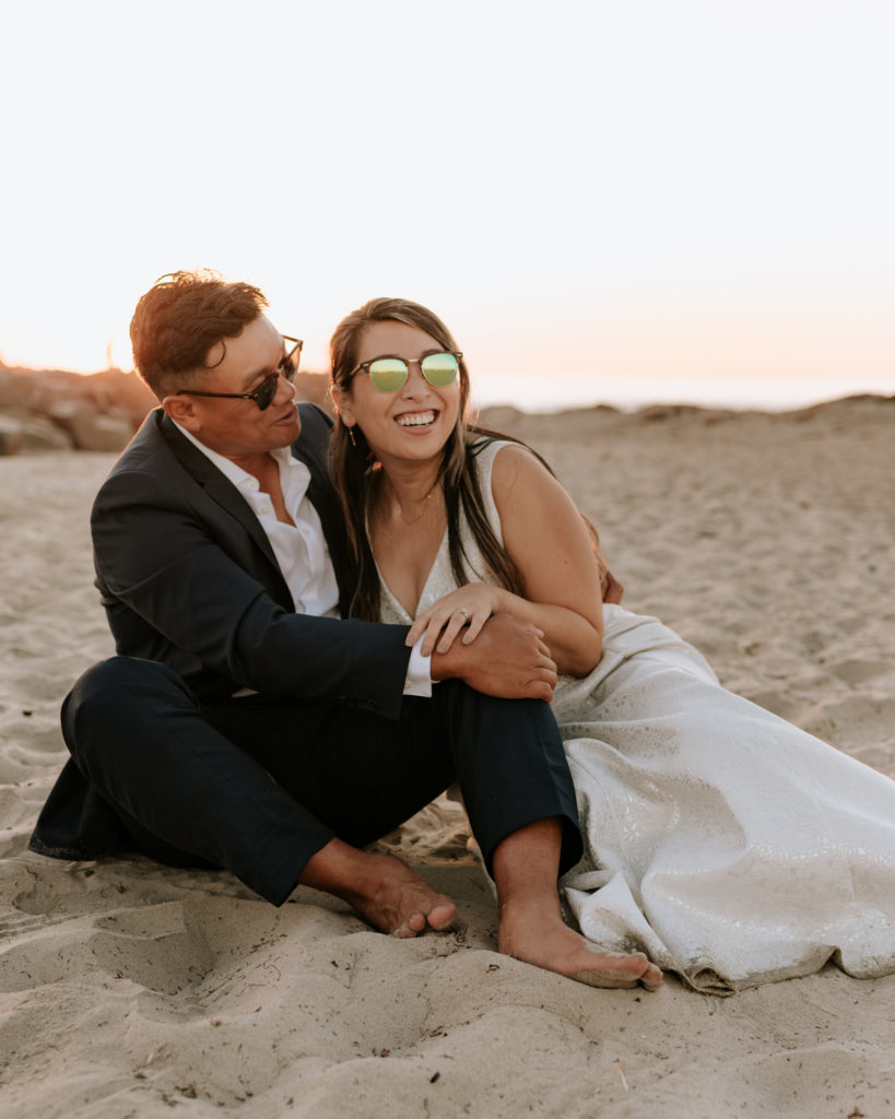 A bride and groom laughing during their elopement at Mission Beach in San Diego.