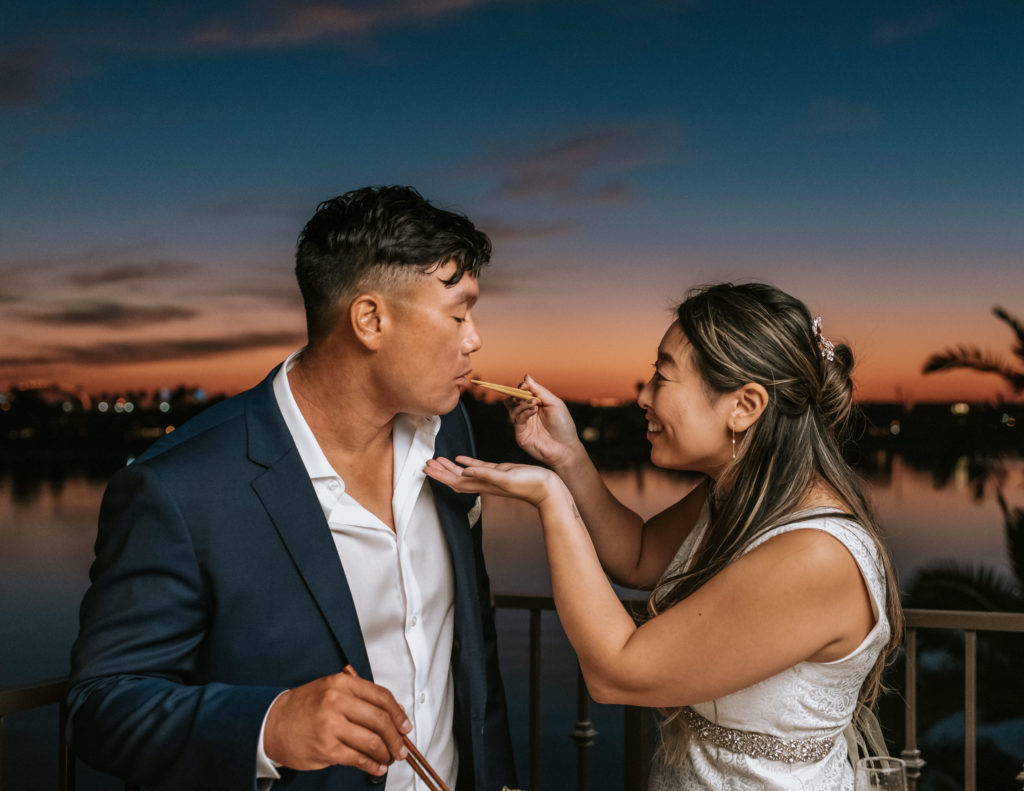 A bride and groom eating during their elopement at the Bahia Resort Hotel in San Diego.