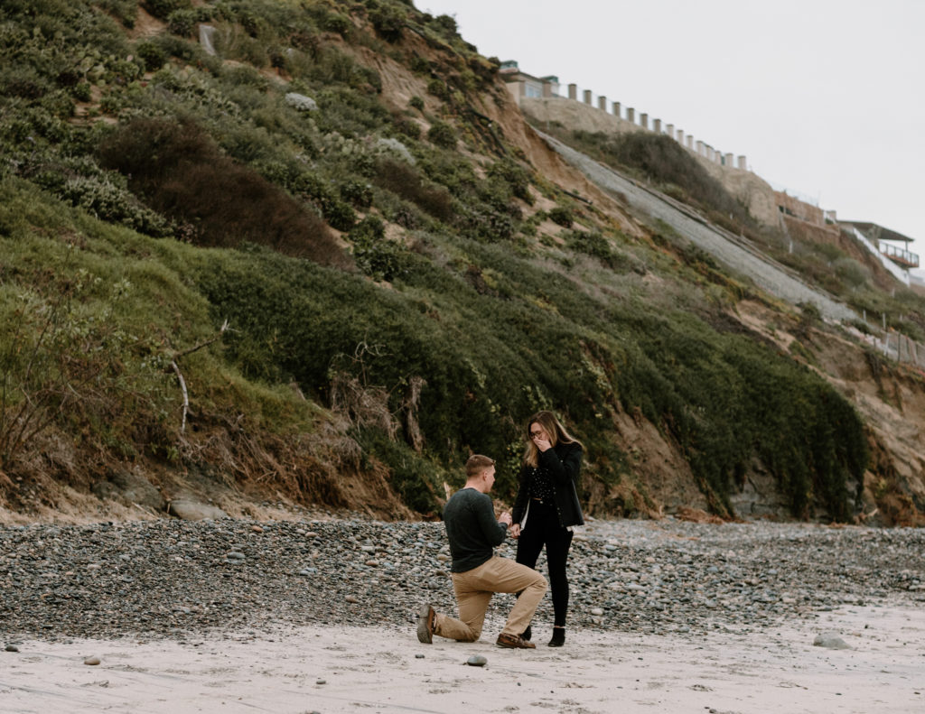 A man surprising his girlfriend with a proposal on the beach in Encinitas, California