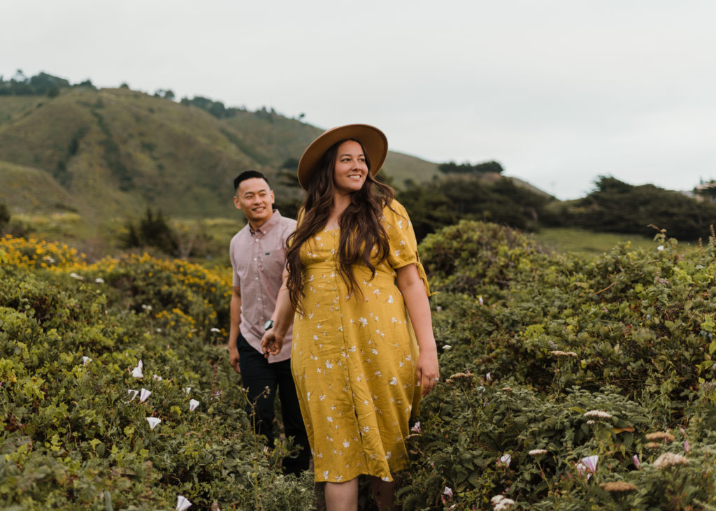 A husband and wife walking in a field in Big Sur during their elopement