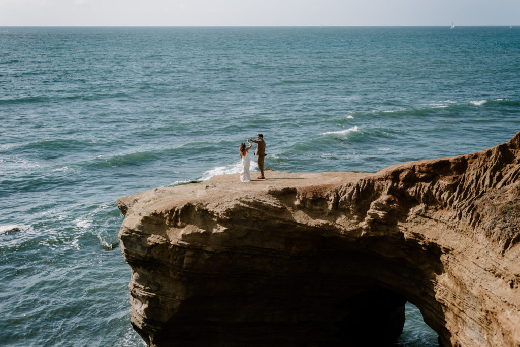 A photograph of a bride and groom dancing during their elopement in San Diego at Sunset Cliffs.