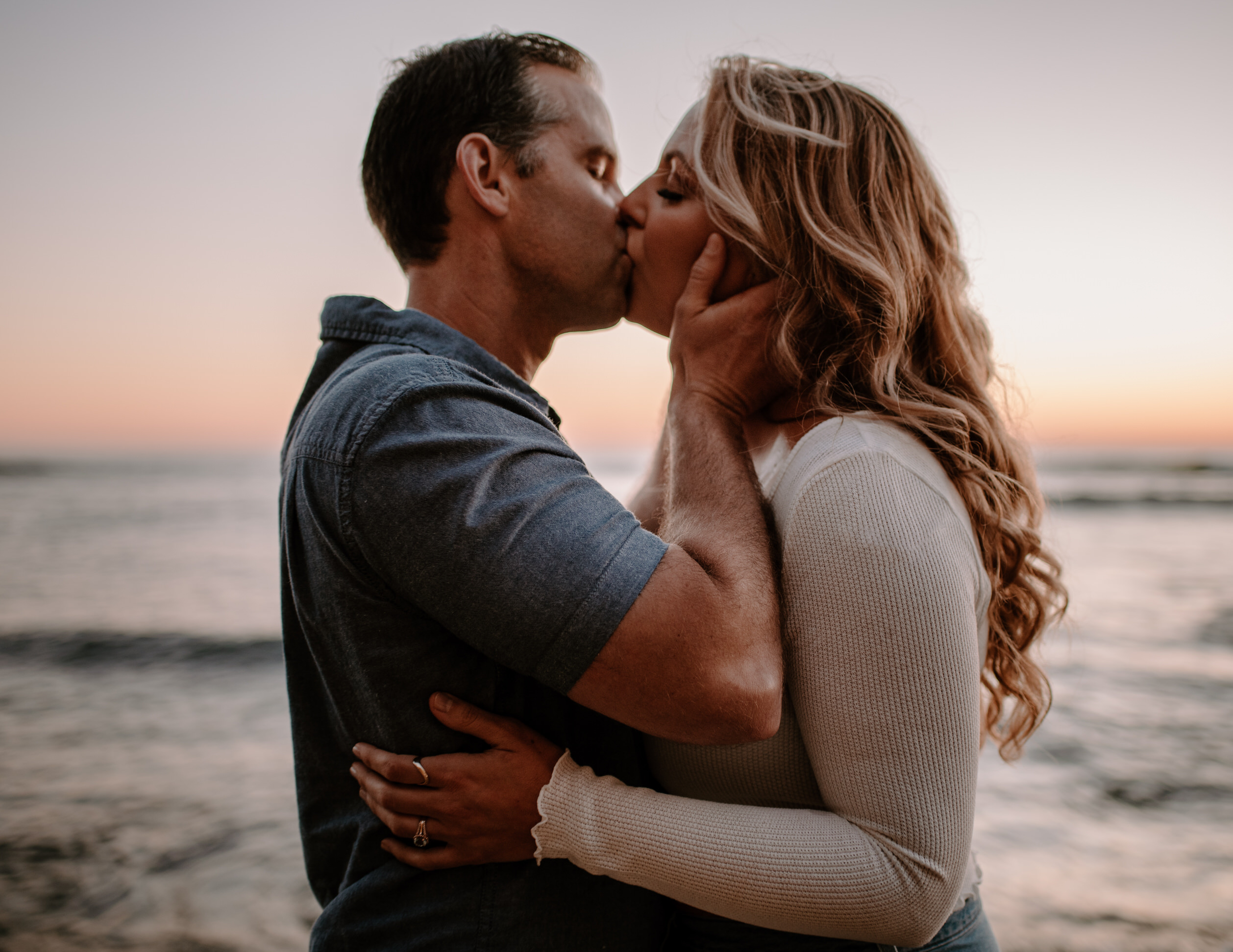 A photograph of a man and woman kissing at Sunset Cliffs during their engagement session.