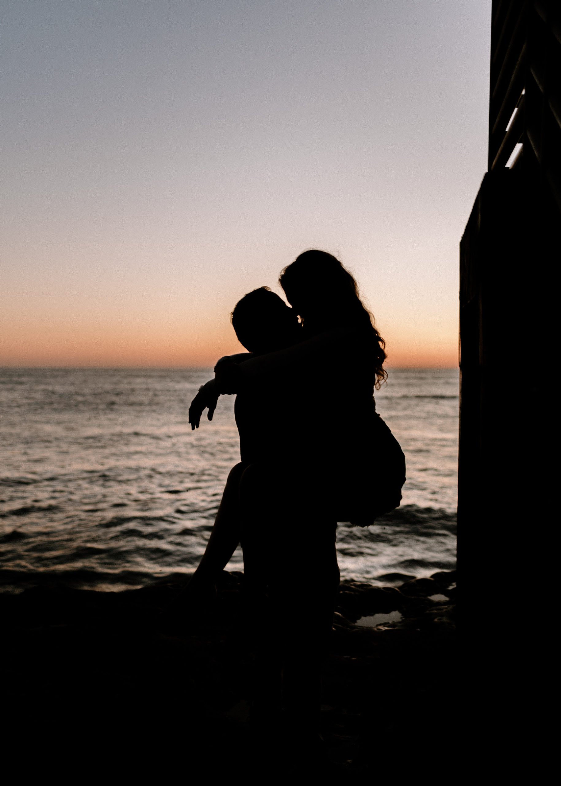A photograph of a man and woman kissing at Sunset Cliffs during their engagement session.