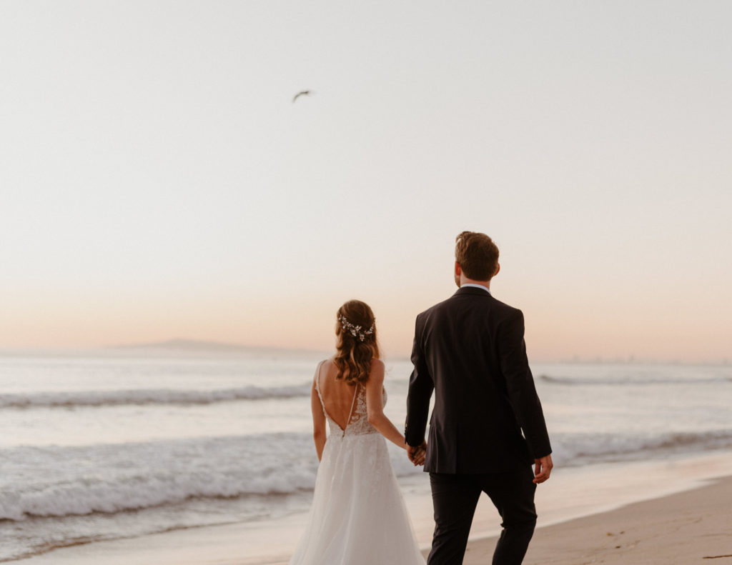 A bride and groom walking at their wedding on Coronado Beach in San Diego, CA.