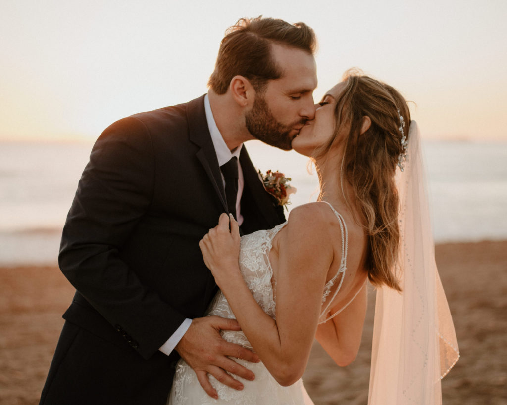 A bride and groom kissing at their wedding on Coronado Beach in San Diego, CA.